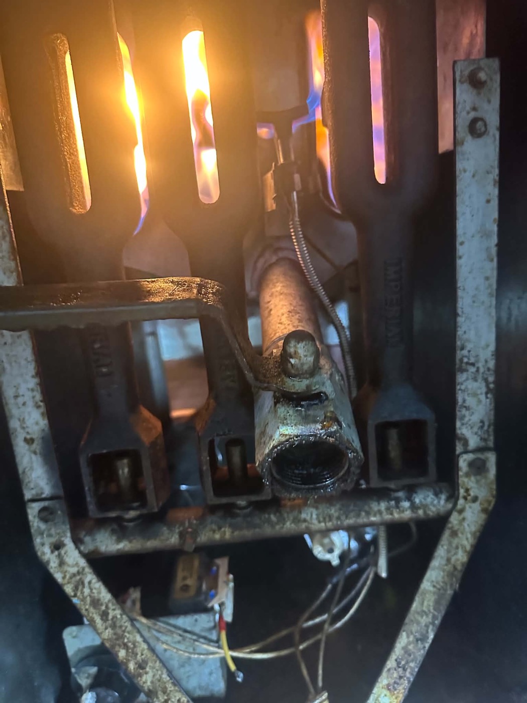 Lit burners inside a commercial gas fryer during servicing